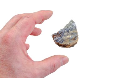 Beyaz arka planda küçük, sert bir mineral kaya örneğini tutan bir el.