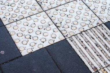 Dokunsal döşeme taşları ve koyu asfalt zemin yüzeyi ayrıntıları kapat