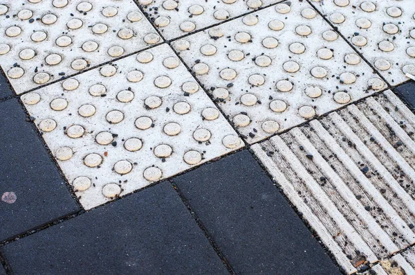 Dokunsal döşeme taşları ve koyu asfalt zemin yüzeyi ayrıntıları kapat