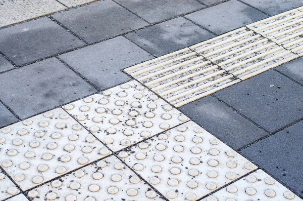 Erişilebilirlik ve güvenlik için şehrin kaldırımında dokunsal kaldırım ve kaldırım taşı dokusu