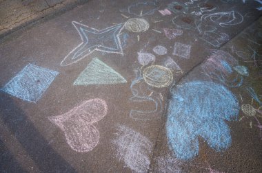 Asfalt kaldırımda çocukların tebeşir ve güneş çizimleri.