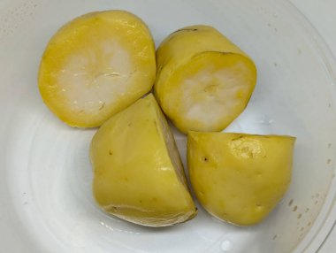 Beyaz plastik kasede soyulmuş ve haşlanmış sarı patates.