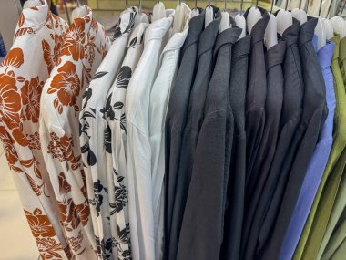 Çiçek desenli ve katı siyah uzun kollu gömlekler askıda asılı.