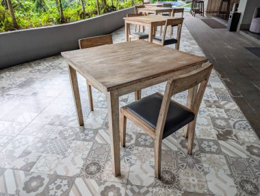 Birkaç basit ahşap masa ve sandalye seti terasa dizilmiştir..