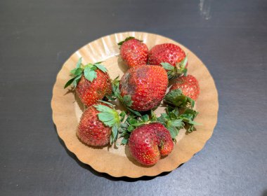 Kağıt tabakta taze ve olgun çilekler.