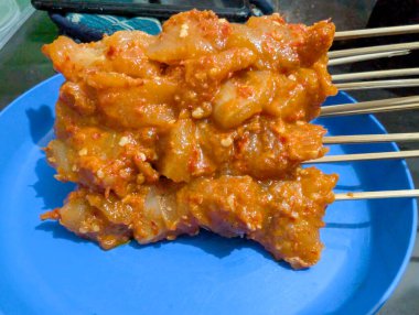 Parlak mavi bir tabağa yerleştirilmiş baharatlarla marine edilmiş tavuk.