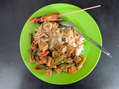 Pirinç ve sebze karışımı ve yeşil tabakta Satay fıstıklı tavuk sosu.