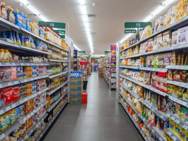Denpasar, Bali, 16 Ocak 2026. Satış raflarında çeşitli ürünlerle dolu bir süpermarket koridoru manzarası.