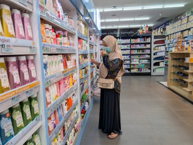 Başörtüsü takan bir kadın Denpasar 'daki bir dükkanda kozmetik ürünlere bakıyor ve onları seçiyor..