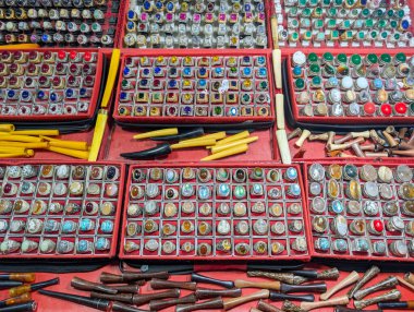 Rengarenk doğal agat taşından geniş bir yüzük koleksiyonu geleneksel bir pazarda sergilenmekte.