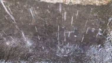 Yere düşen yağmur damlaları şiddetli yağış sırasında su sıçratır.