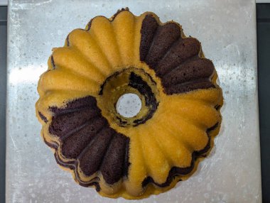 Sarı ve kahverengi renklerin kombinasyonlu mermer pasta, yumuşak desenli ve kendine özgü mermer desenli dalgalı bir kalıpta pişirilmiş..