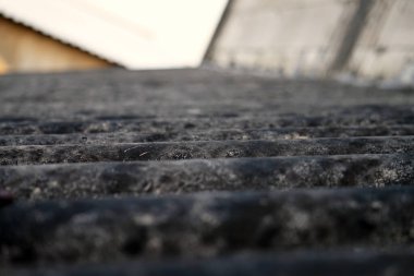 Kirli toprak ve derin dokuyu gösteren eski çatı kaplamalı malzeme dokusunun aşırı yakın çekimi. Düşük açı görünümü arka plan için yıpranmış yüzey ayrıntılarına odaklanır.