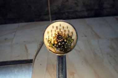 İhmal edilmiş ve çok kirlenmiş bir duş başlığının yakından görüntüsü kötü banyo hijyenini, görünür sert su yataklarının kalıplarını ve küf birikimlerini gösteriyor..