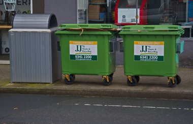 Devonport, Tazmanya, Aust. 22 07 2025. Perakende işyerlerinin dışındaki geçitte, kalıcı bir çöp kutusunun yanında toplanmayı bekleyen yeşil geri dönüşüm kutuları..                                   