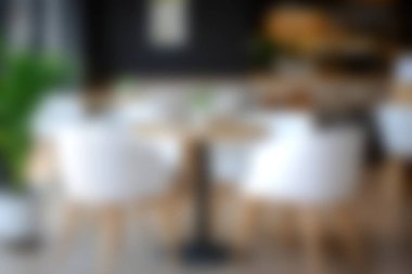 Minimalist mobilyaların, doğal ışığın ve davetkar dekorun bulunduğu rahat, modern bir kahve dükkanının bulanık bir görüntüsü, rahatlama ve sosyal toplantılar için mükemmel..