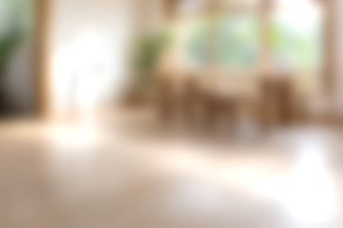 Ahşap yemek alanı ve yemyeşil bitkilerle dolu, berrak ve havadar modern bir oturma odasını tasvir eden yumuşak odaklı bir görüntü..