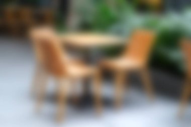 Serin bir açık hava yemek düzeneği. Canlı yeşillikler arasında ahşap sandalyeler ve masa sergileniyor. Huzurlu bir ortamda yemek yemek için mükemmel..