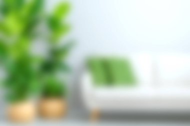 Canlı yeşil bitkilerle dolu beyaz bir kanepenin bulunduğu şık, modern bir oturma odası. Minimalist tasarım sıcak ve davetkar bir atmosfer yaratır..