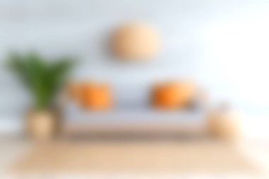 Parlak turuncu yastıklarla bezenmiş, uyumlu ve davetkar bir atmosfer yaratan canlı yeşil bir bitki eşliğinde modern bir kanepenin olduğu rahat bir oturma odası sahnesi..