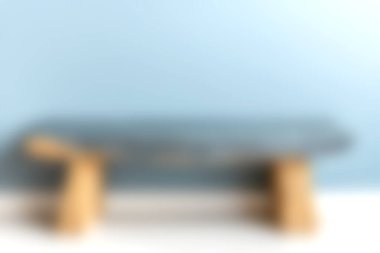 Yumuşak mavi bir arkaplan üzerine kurulmuş şık bir minimalist masa, mobilya tasarımında zarafet sergiliyor ve modern dekorasyon estetiğini sakin bir ortamda gösteriyor..