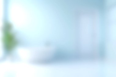 Bu resim, modern bir banyo küveti, yeşil bitki aksanları ve yumuşak mavi tonlardan oluşan parlak ve sakin bir banyo içini gösteriyor. Rahatlamak için huzurlu bir atmosfer sunuyor..