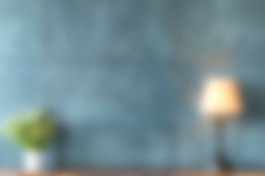 Bu yumuşak odak görüntüsü mavi bir duvar, sıcak bir lamba ve yeşil bir bitki içeren rahat bir iç mekan yakalar. Rahatlamak için mükemmel ve davetkar bir atmosfer yaratır..