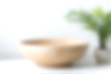 Yeşil bir bitki ile eşleştirilmiş ahşap bir kase içeren yumuşak odaklı bir resim, ev dekorasyonu ve iç tasarım için sakin bir ortam yaratıyor..