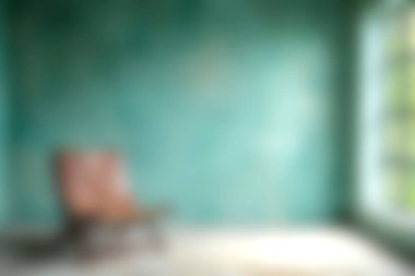 Titrek bir turkuaz duvarın önünde bulanık bir kırsal sandalyenin sıcaklığı ve sükuneti yaydığı sakin ve davetkar bir iç mekan..