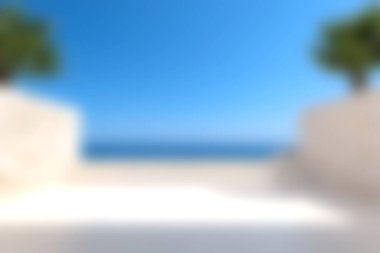 Sade bir sahil manzarası, berrak mavi bir gökyüzü ve sade beyaz mimari tarafından çerçevelenmiş sakin bir okyanus. Rahatlama ve tatil temaları için ideal.