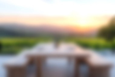 Ahşap masa ve sandalyelerin bulunduğu sakin bir açık hava yemek alanı, büyüleyici bir günbatımı manzarası ile bereketli doğanın ortasına kurulmuş. Toplamak için mükemmel..