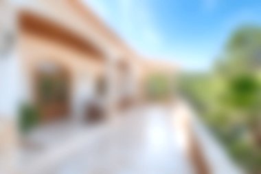 Yumuşak bulanık bir görüntü, canlı yeşillikler ve berrak mavi gökyüzü ile çevrili huzurlu bir terası yakalıyor, rahatlama ve dinginlik için ideal..