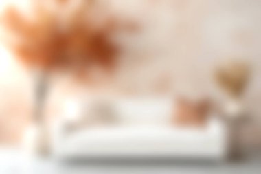 Dekoratif bir çiçek düzeniyle tamamlanmış, rahat ve şık bir atmosfer yaratan, ılık tonlarda yastıklarla süslenmiş, huzurlu bir oturma odası..