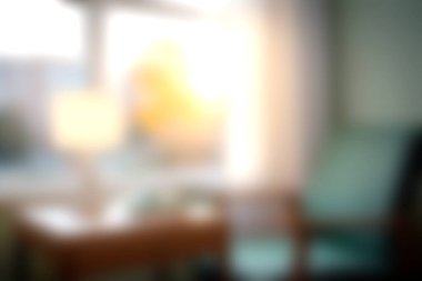 Yumuşak ışıkla dolu rahat bir oturma odası pencereden içeri akıyor rahat bir sandalye ve sıcak bir dekorla rahatlamak için mükemmel bir ortam yaratıyor..