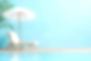 Bu dingin havuz kenarı sahnesi, bir şezlong ve şezlongla, yaz kaçışları için mükemmel, parlak mavi bir arka planda rahatlama ruhunu yakalıyor..