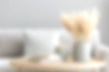 Yumuşak bir vazoda kurumuş çiçeklerin olduğu rahat bir oturma odası sahnesi, yumuşak tekstil eşliğinde, konfor ve sükuneti somutlaştıran sıcak ve davetkar bir atmosfer yaratıyor..