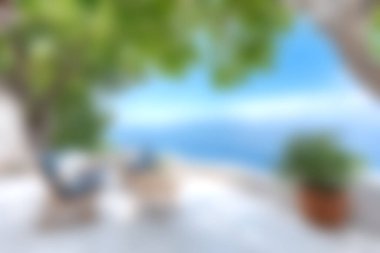 Bereketli ağaçların gölgelediği, parlak mavi bir okyanusa bakan davetkar sandalyelerin olduğu sakin bir sahil sahnesi. Rahatlama ve tatil görüntüsü için ideal.