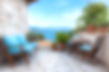 Bu görüntüde mavi yastıklı rahat bir açık hava oturma alanı ve çarpıcı bir kıyı manzarası var. Rahatlamak ve doğada keyif almak için mükemmel..