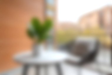 Şık bir masa, rahat bir sandalye ve canlı yeşil bitkiler içeren huzurlu ve modern bir balkon. Rahatlamak ve doğanın tadını çıkarmak için ideal..