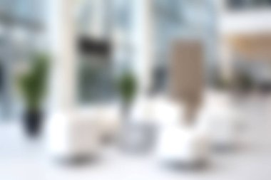 Bu görüntü, konfor ve rahatlama için tasarlanmış, hafif ve havadar bir ortamda yumuşak koltuklar ve yeşillik gösteren modern bir kapalı alan içeriyor..