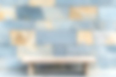 Bu resim ön planda minimalist ahşap bir bank ve modern iç tasarım projeleri için mükemmel olan yumuşak odaklı mavi ve bej desenli bir duvara sahiptir..