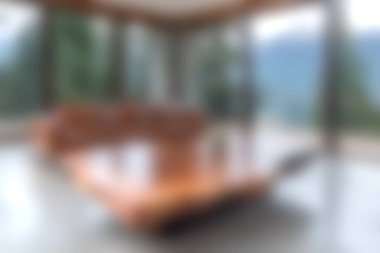 Konforlu, modern bir oturma odası geniş pencerelerden manzarayı bulanıklaştırıyor, ahşap mobilyalar ve sakin bir atmosfer için minimalist bir tasarım sunuyor..