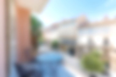 Sakin bir manzaranın bulanık arka planı ve mavi gökyüzü karşısında şık sandalyeler ve bir masa içeren rahat bir açık alan..