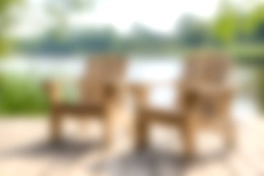 Huzurlu bir gölün kenarındaki rahat, ahşap sandalyelerin huzur veren güzelliğinin tadını çıkarın. Doğanın yeşilliği ve yumuşak güneş ışığı altında rahatlamaya davet edin..