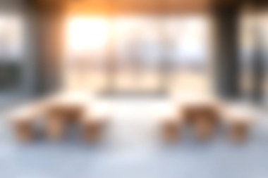 Yumuşak doğal ışıkla aydınlatılmış, gevşeme ve sosyal etkileşim için ayarlanmış ahşap mobilyaların yer aldığı sakin, açık bir alan..