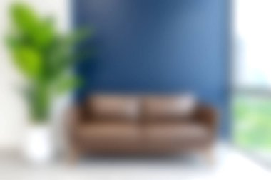 Parlak ve davetkar oturma odasında kahverengi bir kanepe, kapalı bir bitki ve modern ev dekorasyonu için mükemmel bir mavi duvar var..