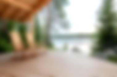 Bulanık ahşap bir güverte ve kır sandalyeleri içeren sakin bir göl manzarası, doğal ortamlarda rahatlamak için mükemmel..