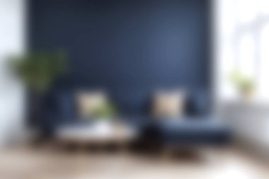 Dekoratif yastıklarla süslenmiş, karanlık bir duvar ve doğal ışık ile tamamlanmış şık mavi bir kanepenin yer aldığı rahat, modern bir oturma odası, davetkar bir yer yaratıyor..