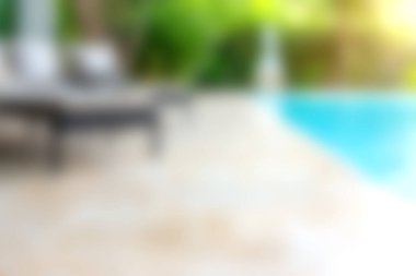 Bu görüntü, bulanık elementlerle sakin bir havuz kenarı görüntüsü yakalar. Mavi su ve dinlenmek için mükemmel sakin bir atmosfer sunar..