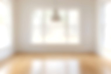 Bu resim, modern tasarım ortamında ahşap bir zemini aydınlatan, geniş pencerelerden yayılan doğal ışıkla aydınlık ve havadar bir iç mekan sergiliyor..